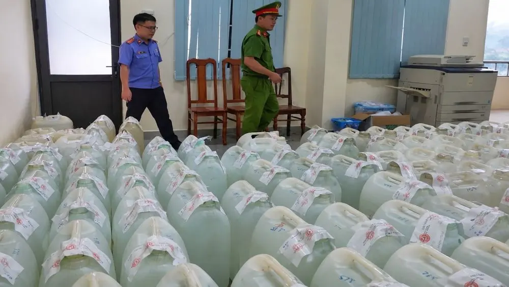 Người phụ nữ bị khởi tố vì pha cồn với nước thành rượu bán. Hàng trăm can rượu đã bị cơ quan chức năng niêm phong.
